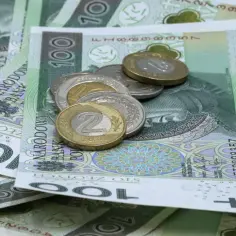 Stos polskich banknotów 100 zł i monet, w tym 2 zł.
